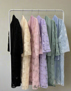 Set of lace dresses in various colors hanging on a rack against a white wall.